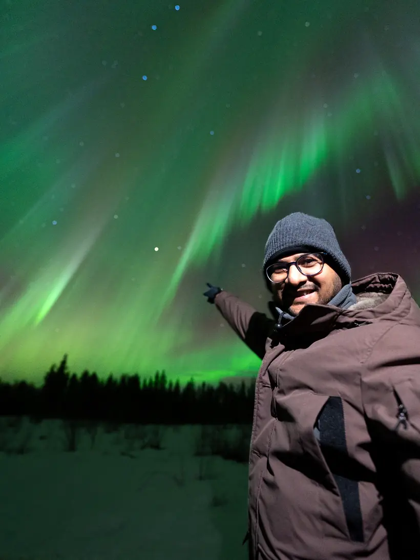 Guest pointing at the aurora borealis on a northern lights hunting tour