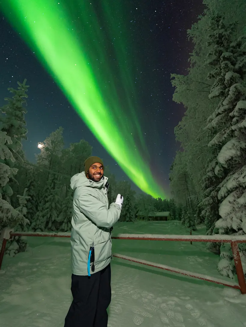 Aurora borealis arching over a snowy forest road in Lapland