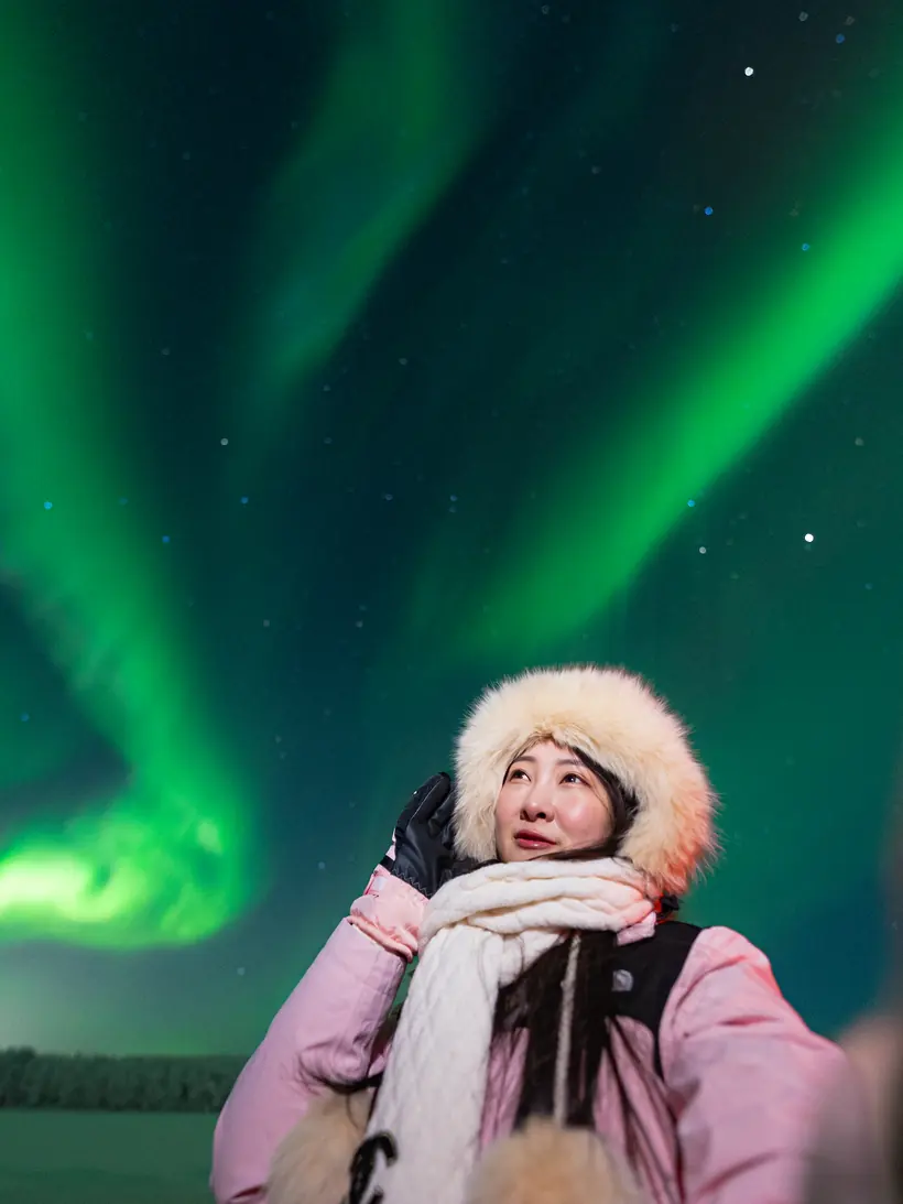 Guest looking up at the northern lights in a fur hat