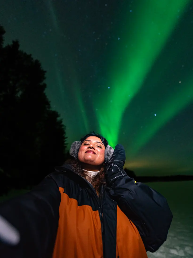 Guest smiling under the aurora on an aurora hunting night
