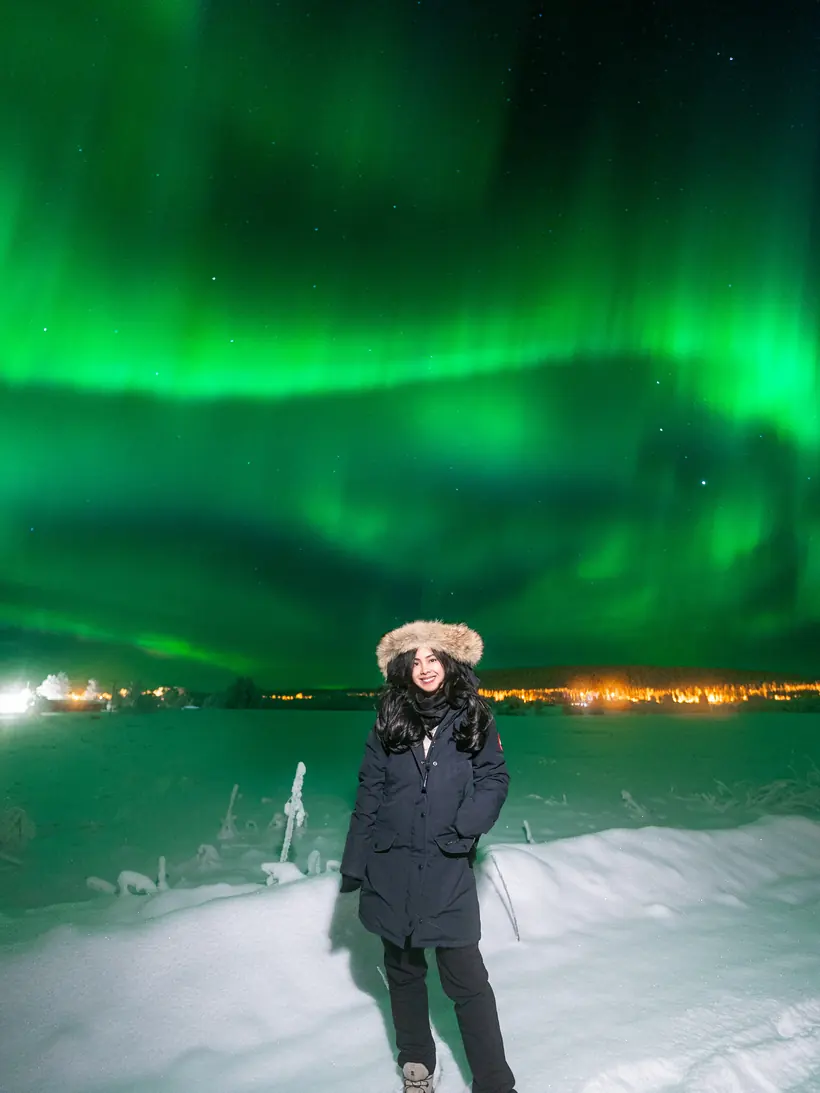 Bright aurora borealis corona above a guest in the snow
