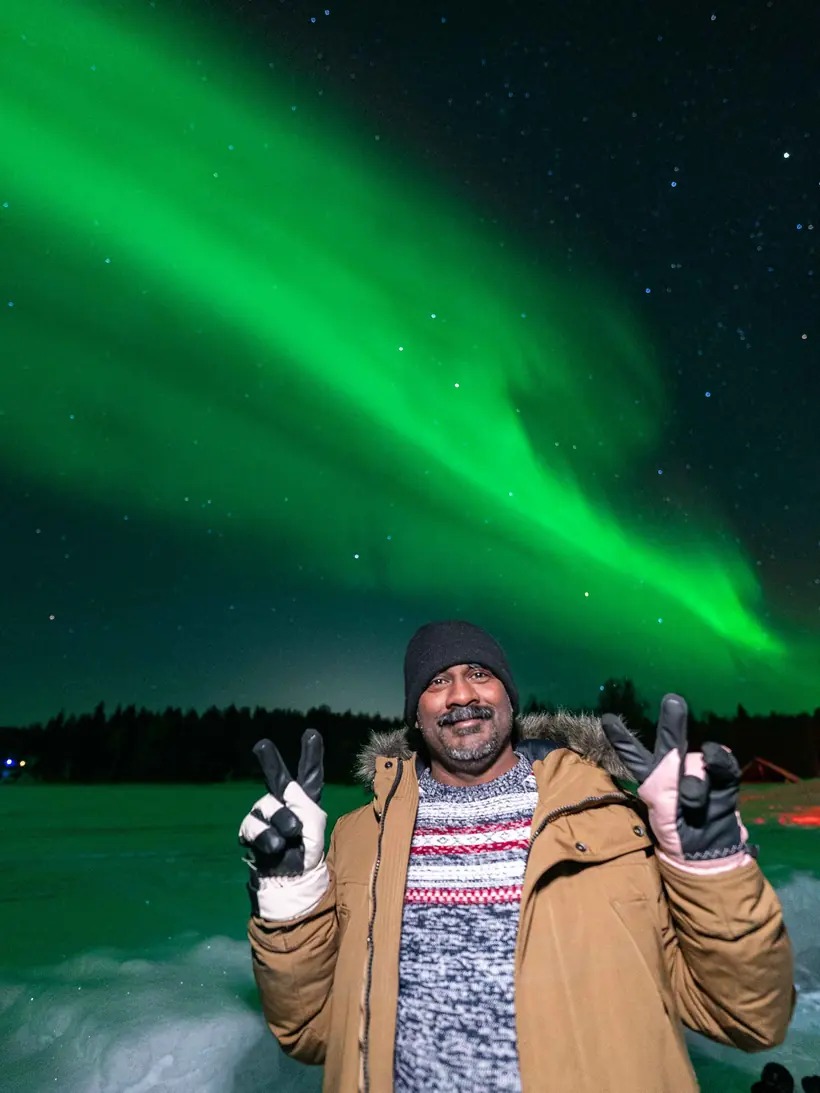 Guest making peace signs under a wide aurora band